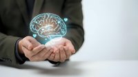 Professional businessman holding glowing digital brain hologram in cupped hands representing artificial intelligence, innovation and mental health concepts.