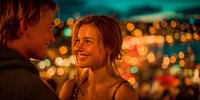 Young couple enjoying romantic evening date with warm bokeh city lights creating intimate atmosphere for relationship and love moments.