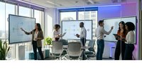 Modern business team collaborating in bright conference room with interactive displays and city view windows during strategic planning meeting.