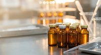 Amber glass vials in modern laboratory setting for pharmaceutical research and drug development with scientific equipment in background.