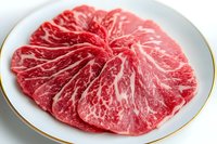 Raw marbled beef steak with distinctive white fat pattern on white plate with gold trim, showcasing premium meat quality and luxurious marbling texture.