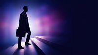 Silhouette of male professional in dark suit and briefcase standing on illuminated pathway with purple and blue glowing light effects, representing career advancement and business opportunity.