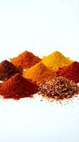 Colorful spice powder piles with crushed red pepper flakes on white background for culinary cooking and seasoning applications.
