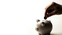 Hand dropping coin into white piggy bank for savings and financial planning on clean background.