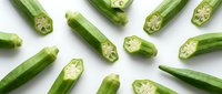 Fresh green okra pods sliced and whole scattered on white background. Healthy organic vegetable ingredient for cooking and nutrition concepts.