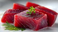 Fresh raw tuna steaks with herbs on white background, premium sashimi grade fish fillets for cooking, healthy protein rich seafood ingredient.
