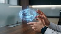 Young male professional with medium skin tone wearing business casual attire and smartwatch, holding holographic digital gear icon in office environment, representing technology innovation and engineering solutions.