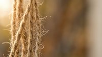 Natural jute rope fiber texture with warm sunlight creating golden glow and soft bokeh background for rustic nautical and craft projects.