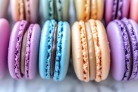 Colorful French macarons in pastel purple, blue, and peach shades arranged in row showing delicate almond meringue cookies with creamy filling, macro food photography.