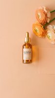 Amber dropper bottle with face oil label on peach background beside orange ranunculus flowers, elegant flat lay for beauty and skincare branding.