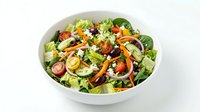 Mixed green salad with fresh vegetables, nuts and dressing in white bowl on white background, isolated for food packaging and restaurant menus.