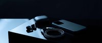Modern wireless earbuds with charging case and cable on minimalist surface. Contemporary audio technology for music, calls, and entertainment.