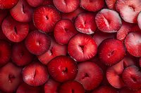 Fresh sliced red plums arranged in a pattern showing vibrant flesh and deep crimson color, creating natural organic background texture for food design.