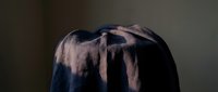 Silhouette of a person wearing a hooded garment with dramatic lighting creating shadows and texture, suitable for concepts of mystery, anonymity, or contemplation.