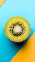 Fresh kiwi fruit slice on vibrant geometric background with turquoise and yellow colors for healthy eating and nutrition concepts.