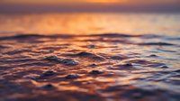 Ocean waves at golden hour with warm sunset light reflecting on water surface creating peaceful seascape for meditation and relaxation backgrounds.