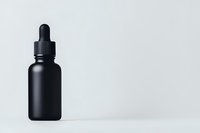 Matte black glass dropper bottle on white background, minimalist composition for cosmetic, pharmaceutical or essential oil packaging design mockup.