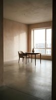 Minimalist interior space with wooden table, single chair, and potted plant by large window overlooking urban cityscape, concrete flooring, neutral beige walls, natural daylight, modern apartment design.