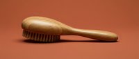 Wooden hairbrush with natural bristles on a warm terracotta background, showcasing eco-friendly grooming tools for hair care and beauty concepts.