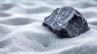 Raw black stone on white sand creates minimalist composition with soft focus background, highlighting natural texture and geological formation in monochromatic style.