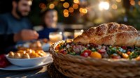 Fresh baked croissant with sesame seeds on woven basket filled with colorful candy against blurred festive background with warm bokeh lights.