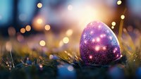 Magical Easter egg with galaxy pattern and sparkles resting in grass at dusk, surrounded by soft bokeh lights creating dreamy atmosphere.