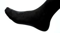 Close-up of a foot wearing a black sock on a white background, isolated for fashion, retail, and clothing design use.