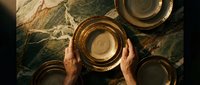 Person holding wooden bowl on marble surface with additional bowls arranged around, overhead view for culinary, food styling, and tableware design projects.