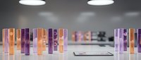 Colorful cosmetic bottles and tubes arranged on white surface in modern laboratory or beauty product development workspace with soft lighting.