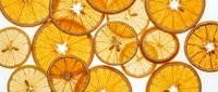 Dried orange and lemon slices arranged on white background, showcasing translucent citrus cross-sections with natural segments and vibrant golden tones for culinary and decorative uses.