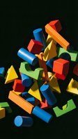 Colorful geometric wooden blocks and cylinders in red, blue, yellow, orange, and green arranged in dynamic composition against dark background for educational and creative design projects.