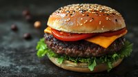 Gourmet cheeseburger with sesame seed bun, melted cheddar, tomato, and lettuce on dark slate surface for food photography and restaurant marketing.