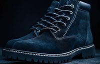 Navy blue suede boot with white contrast stitching and rugged sole on dark background, showcasing detailed craftsmanship and durable construction for footwear design.