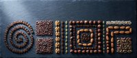 Assorted premium chocolate candies and truffles arranged in geometric patterns on dark slate surface for confectionery and dessert presentations.