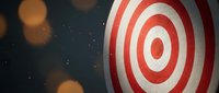 Red and white bullseye target with concentric circles against dark background with golden bokeh lights for business goals and achievement concepts.