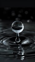 Crystal clear water drop forming a spherical shape on stem-like water column against dark background with concentric ripples and reflections in liquid surface.