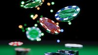 Colorful casino chips floating in air against dark background with green felt table surface, creating dynamic gambling atmosphere with motion blur effect.