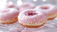 Pink frosted donut with raspberry jam filling and powdered sugar on cooling rack, soft bokeh background creates dreamy dessert atmosphere.