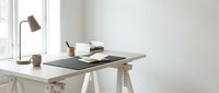 Minimalist home office workspace with wooden desk, laptop, coffee cup and desk lamp in bright white interior for productivity and remote work.