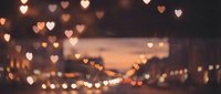 Romantic heart-shaped bokeh lights creating dreamy atmosphere over blurred city street at dusk. Perfect for Valentine's Day, love themes, and romantic designs.