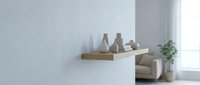 Modern minimalist floating wooden shelf with ceramic vases and books on white wall in contemporary living room interior with natural light and plants.