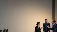 Professional business team meeting in modern conference room with colleagues discussing strategy and shaking hands after successful negotiation.