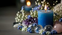 Blue candle burning surrounded by healing crystals, gemstones and dried flowers creating peaceful meditation and wellness atmosphere for relaxation.