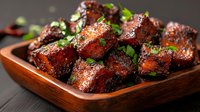 Grilled chicken wings glazed with sweet and spicy sauce, garnished with fresh herbs in wooden serving bowl, close up view of appetizing party food.