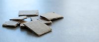 Broken wooden puzzle pieces scattered on white surface showing fragmented parts of jigsaw game ready for assembly and problem solving activities.