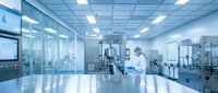 Scientist in white protective suit working in modern sterile laboratory with advanced equipment and glass partitions for pharmaceutical research.