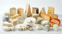 Assorted gourmet cheese collection featuring hard, soft, blue and aged varieties arranged on white background for culinary and food photography.