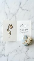 Open sorry card with wilting flower illustration beside a kintsugi ceramic heart on marble, conveying apology, healing, and emotional renewal.