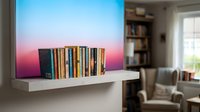 Colorful book collection displayed on modern white floating shelf against gradient blue to pink wall in contemporary living room interior.