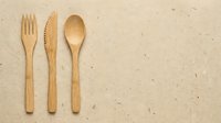 Wooden fork, knife, and spoon arranged on beige textured background, isolated eco-friendly utensils for sustainable dining, catering, and kitchen design projects.